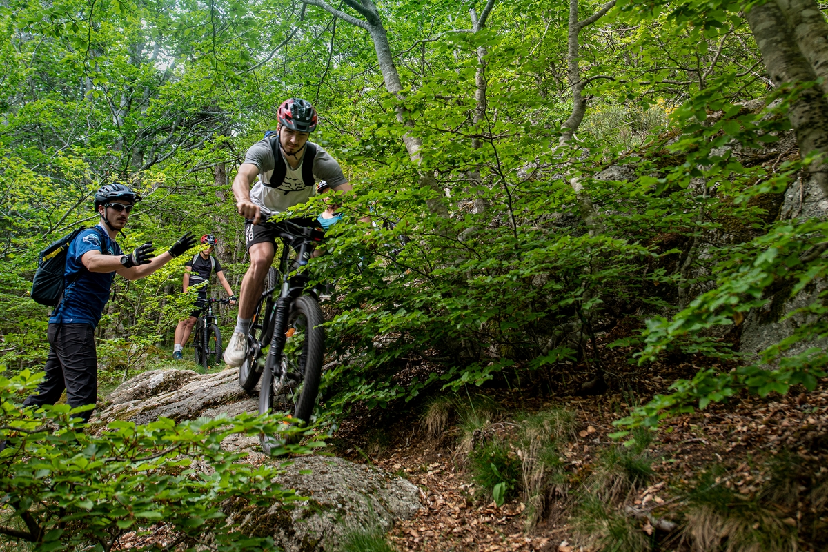 un vététiste est sur une dalle rocheuse, le mponiteur de VTT MCF fait une parade