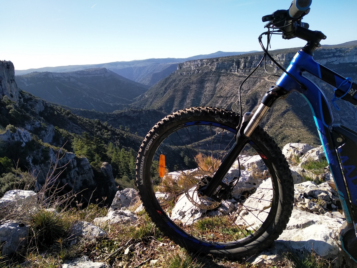 un VT avec de gros crampons sur son pneu avant semble observerr els gorges de la Vis depuis les belvédères de Blandas
