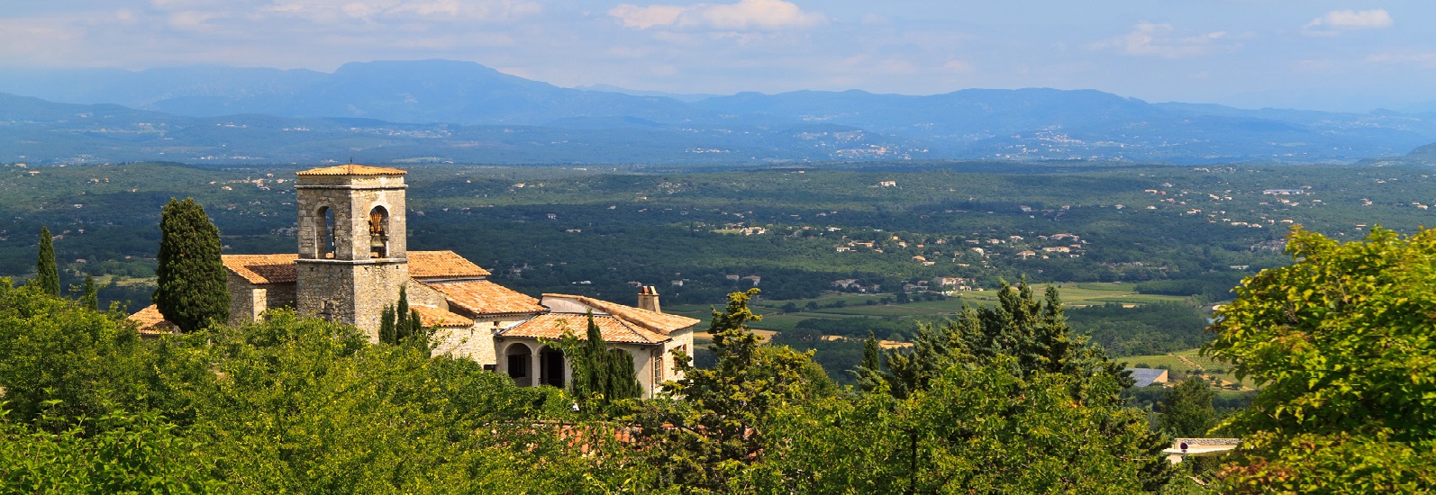 un village méridional, la plaine ardéchoise et les montagnes en arrière plan 